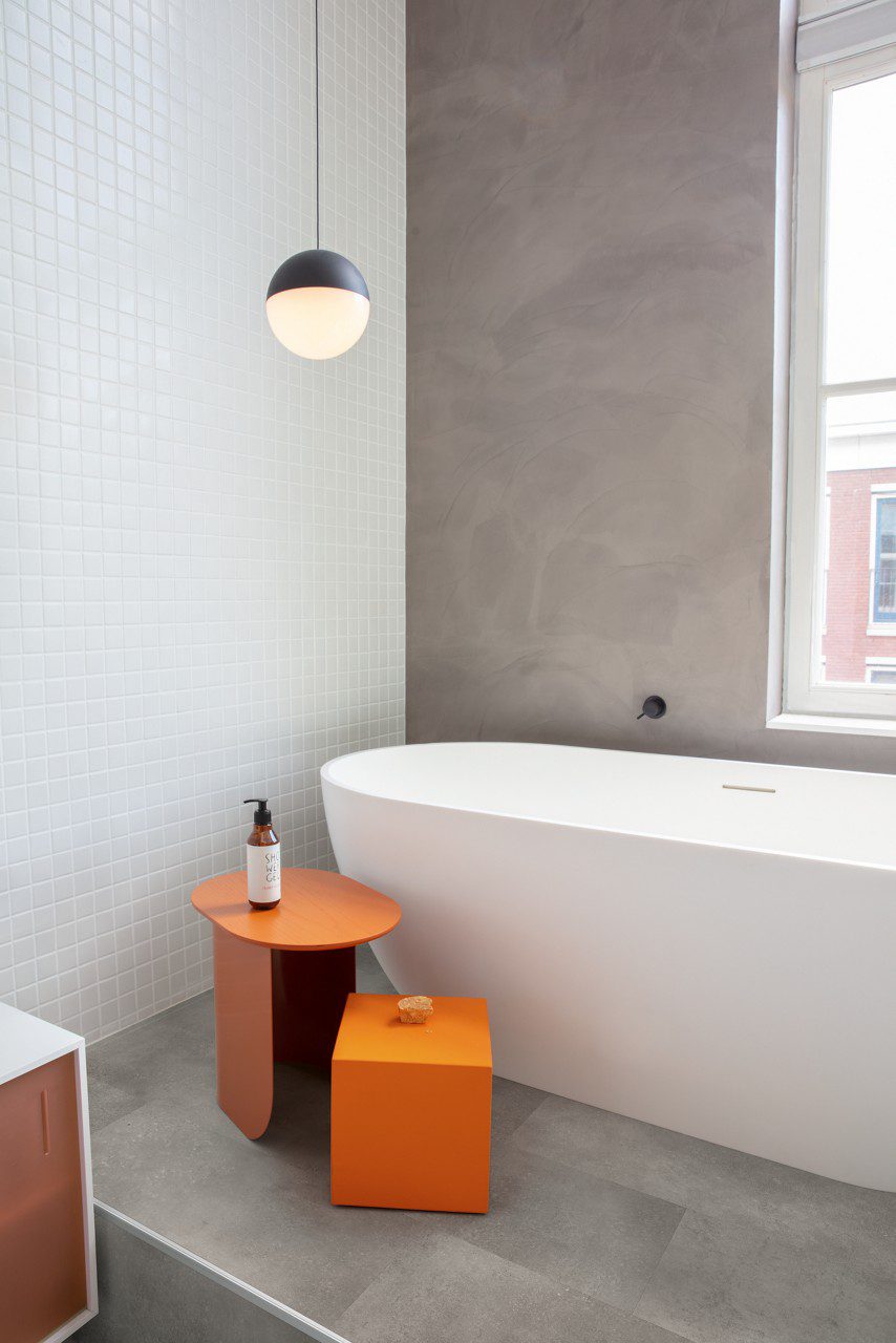 LVT plaat Quick-Step Oro Concrete rock paigaldatud vannitoa põrandale. Eraldiseisev valge vann, oranzh tarvikute laud.