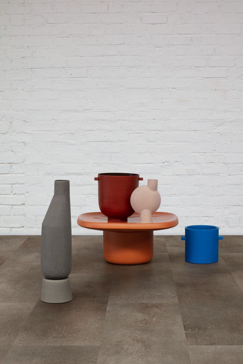 Vinyl Tiles Quick-Step Oro Oxidized rock installed on a hallway floor. White bricks wall, table, vases.