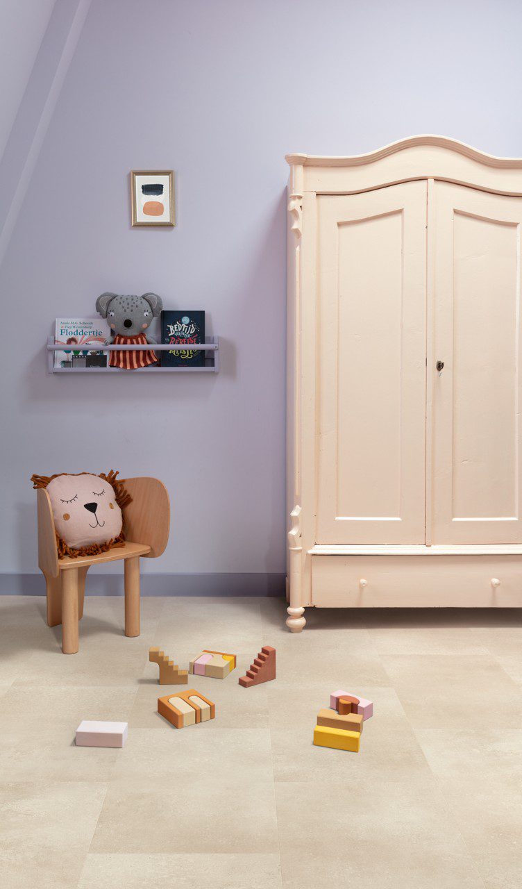 Vinylboden Stein Quick Step Oro Coral Rock im Kinderzimmer verlegt warme korall sandfarbene Steinoptik natürliche Struktur und dezente Farbvariationen klassischer Kinderzimmerschrank kleiner Stuhl mit Kissen im Löwen Design und Spielzeug auf dem Boden