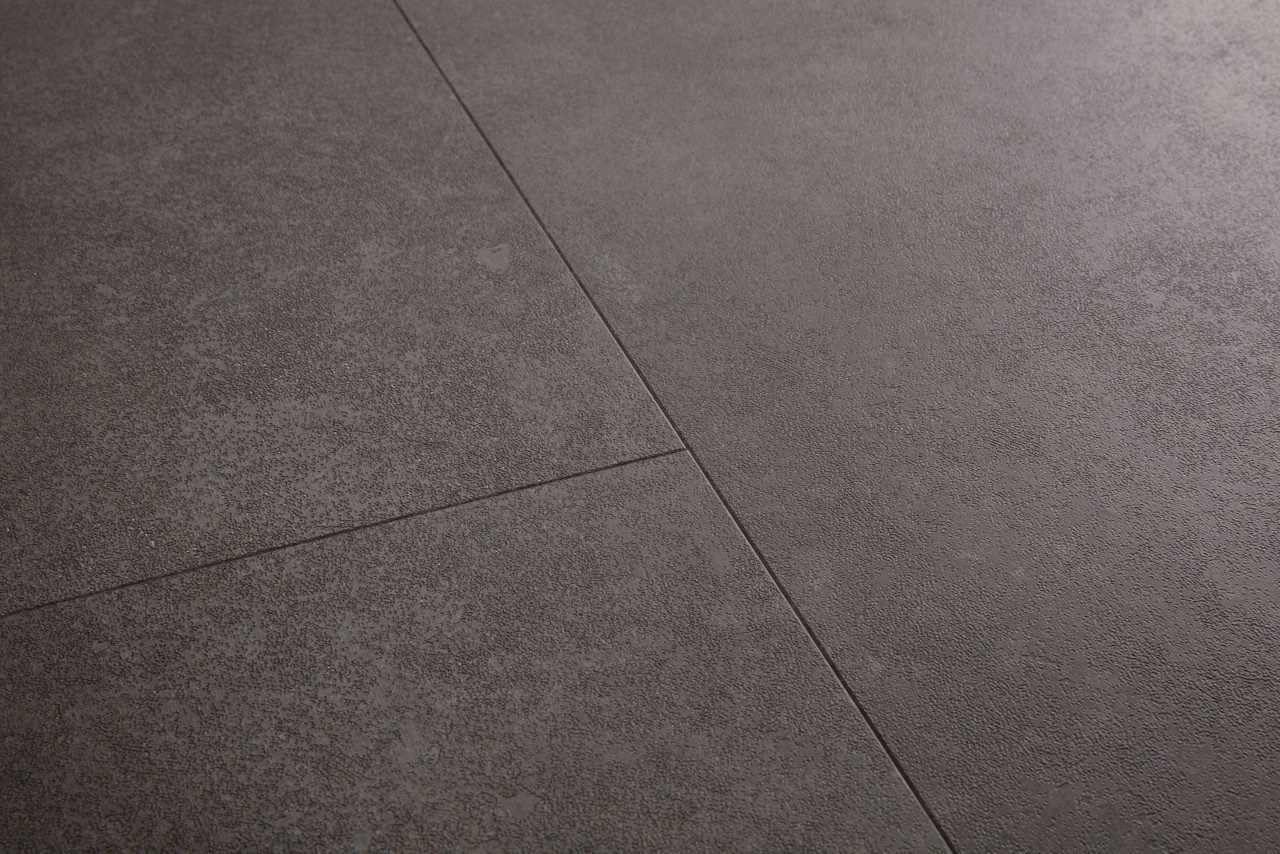 Vinyylilaatta Quick Step Oro Volcanic Rock asennettu lattialle tumma grafiitinharmaa vulkaaninen kivisävy moderni kivikuosi hienovarainen kivipinnan struktuuri ja luonnollinen sävyvaihtelu kestävä ja helppohoitoinen vinyylilattia sisustuksessa