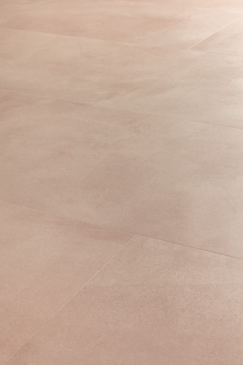 Vinyylilattia Quick-Step Illume Soft Blush asennettuna kodin lattialle – vaalea, pehmeän roosabeige (blush) sävy ja hillitty kivimäinen/betonimainen design hienovaraisella tekstuurilla.