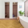 herringbone-laminate-floor-quick-step-impressive-design-cumin-oak Herringbone laminate floor Quick Step Impressive Design Cumin Oak, installed on bathroom floor with a white bathtub