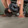 klick-vinyl-quick-step-bloom-cotton-oak-cozy-grey Klick Vinylboden Quick Step Bloom Cotton Oak Cozy Grey im Homegym verlegt, ein Mann hebt eine Hantel.