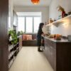 Quick Step Bloom Pure Oak Polar rigid vinyl flooring installed on a kitchen floor, a woman washing vegetables, brown kitchen cabinets.