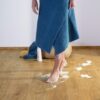 Vinyylilattia Quick Step Blos Cottage Tammi Natural asennettuna lattialle samansävyisten jalkalistojen kanssa, luonnollinen tammen sävy ja lankkulattia tammi, nainen kävelee lattialla märin ja vaahtoisin jaloin.