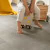 LVT parkett Quick-Step Oro Concrete rock paigaldatud lastetoa põrandale. Laps istub ratastega tumbal.