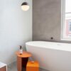 LVT plaat Quick-Step Oro Concrete rock paigaldatud vannitoa põrandale. Eraldiseisev valge vann, oranzh tarvikute laud.