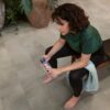 Frau sitzt auf einer Bank und trinkt Wasser im Home-Gym – der Vinylboden in Betonoptik (Quick-Step Oro Concrete Rock) ist auf dem Boden verlegt.