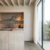 Vinylboden in Steinoptik Quick-Step Oro Concrete Rock, verlegt auf dem Küchenboden – Kücheninsel mit Betonarbeitsplatte und moderne Küchenschränke.